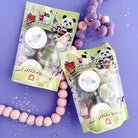 Two packages of bubble tea toys on a purple background with decorative beads.
