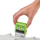 Hand using a green cartoonish stamp on a white shirt