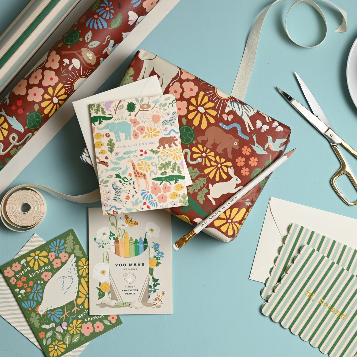 Assorted stationery items including notebooks, cards, and ribbons on a light blue background