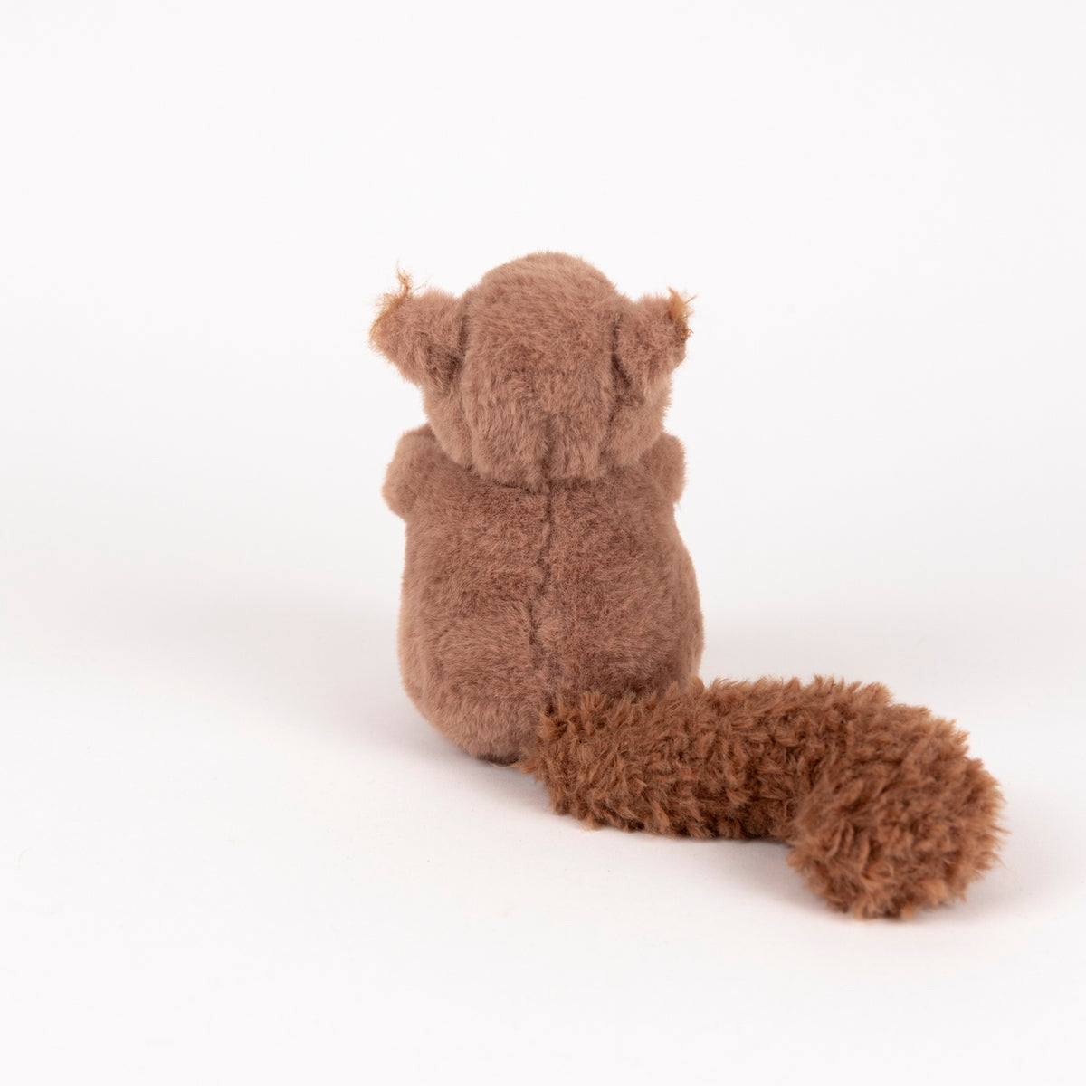A brown plush squirrel toy shown from the back, featuring a fluffy tail and small ears, photographed on a seamless white background.