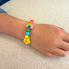 Colorful beaded bracelet with rainbow and flower designs on a wrist against a neutral background
