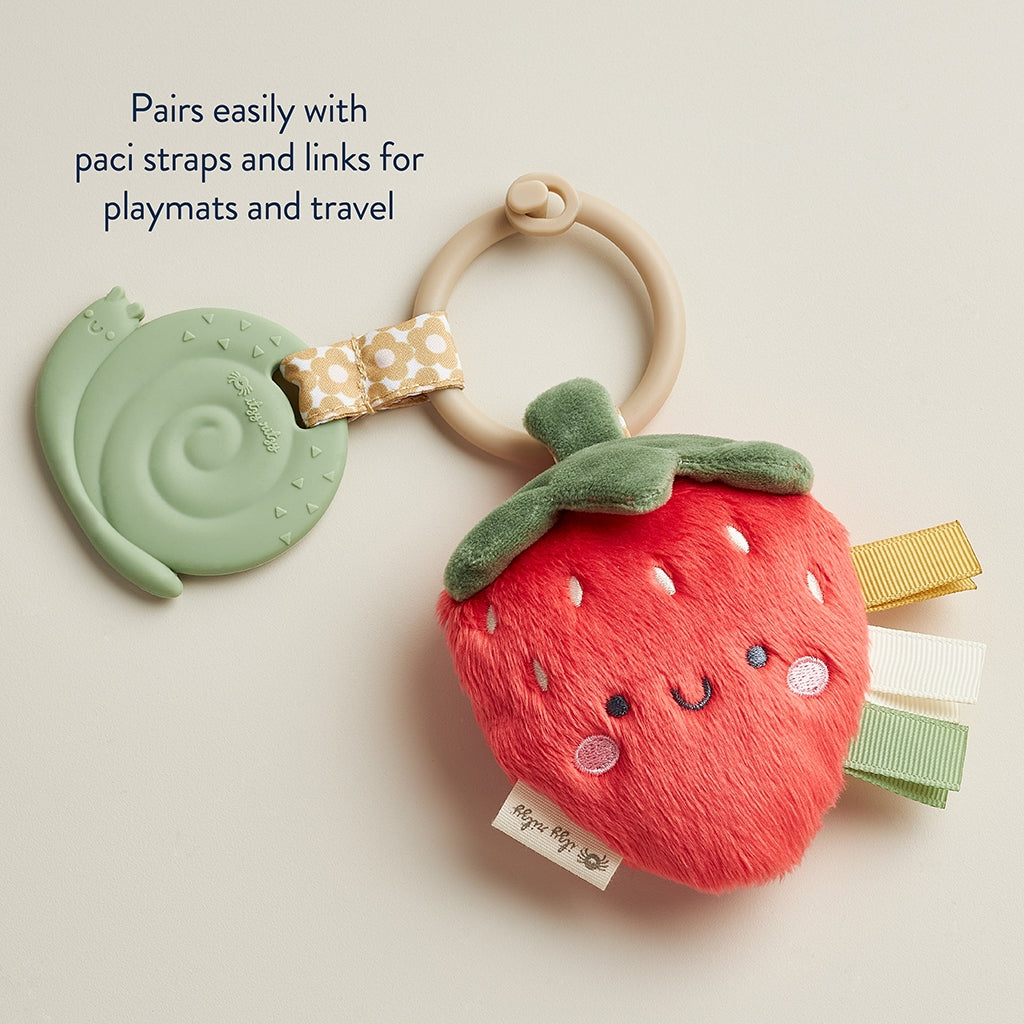 Strawberry-shaped toy with pacifier clip and teether on a light background