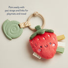 Strawberry-shaped toy with pacifier clip and teether on a light background