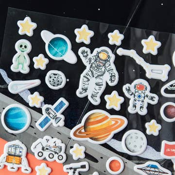Collection of space-themed stickers on a black background with stars and planets.