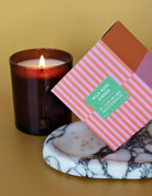 Candle with a decorative box labeled 'Wild Rose Ginger' on a marble coaster.