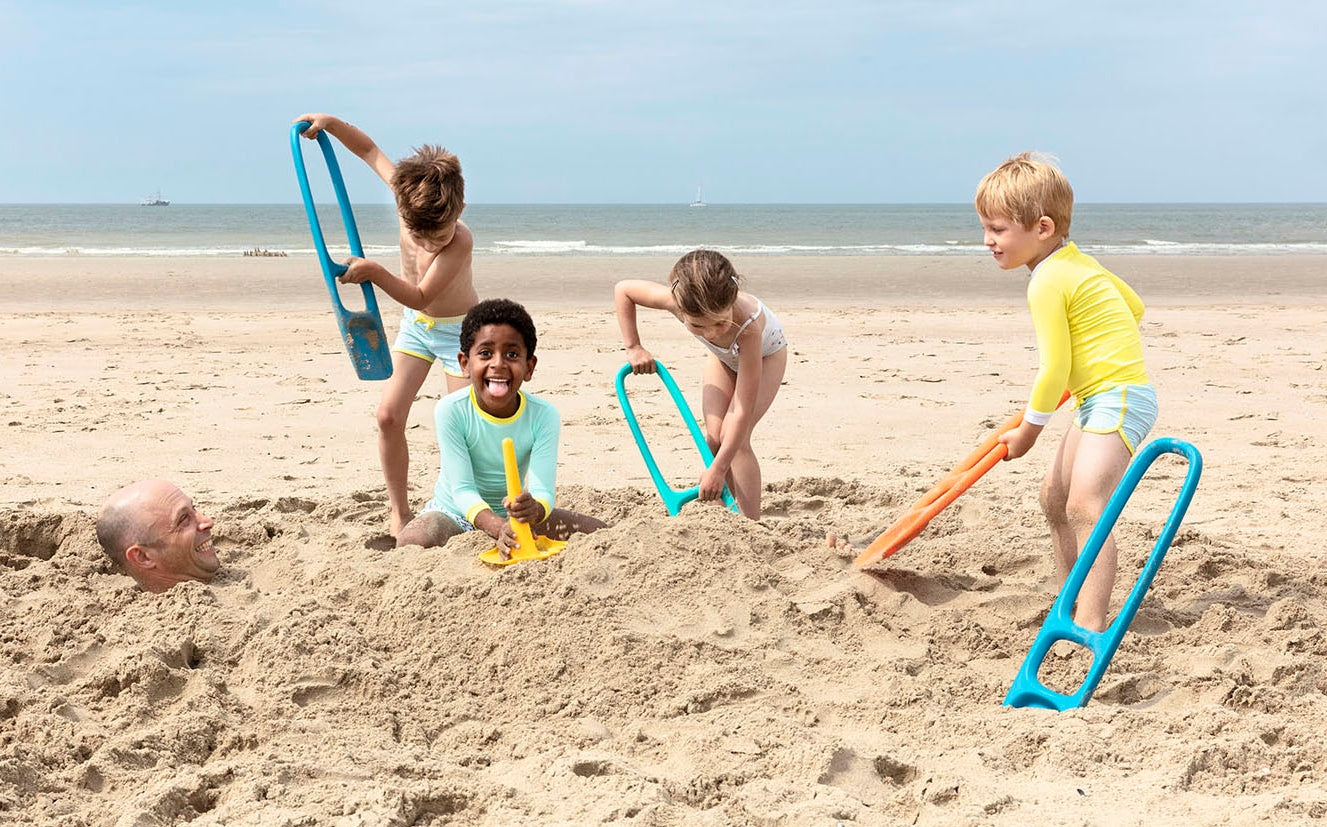 Children playing in the sand on a beach with toys
