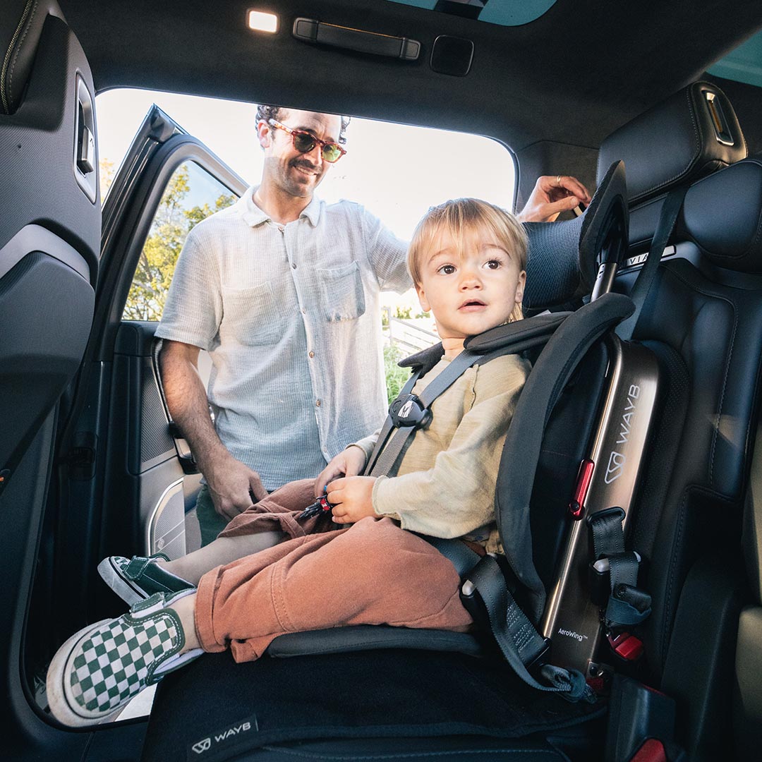 Child in a car seat being helped by an adult in a vehicle