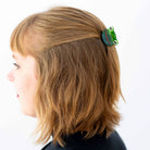 Person with a green hair clip featuring a frog design in their hair on a white background