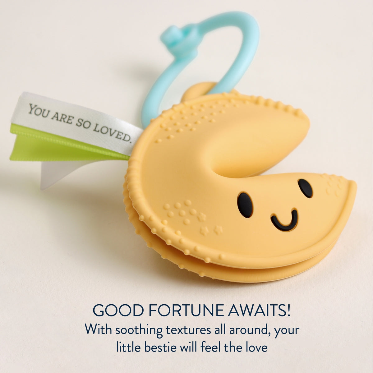 Yellow teething toy with a smiley face on a light beige background