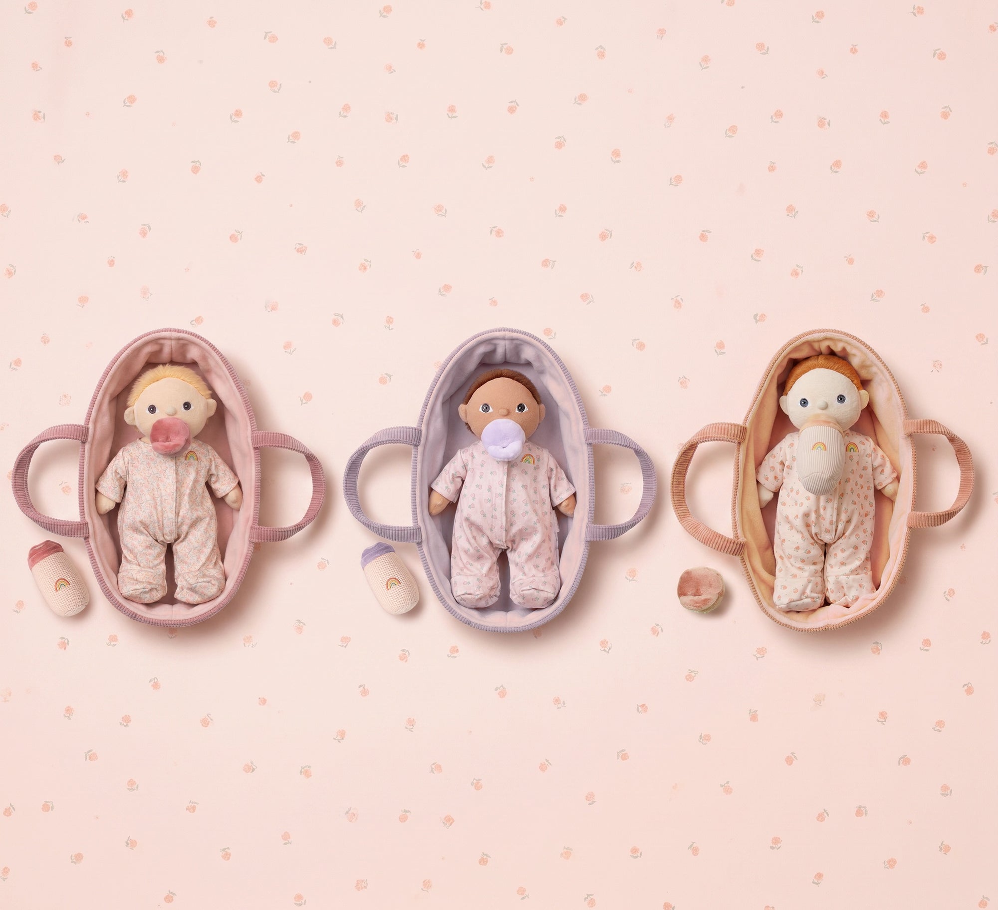 Three baby模拟器 in different colors on a pink background with small white dots.