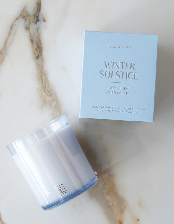 Candle and packaging labeled 'Winter Solstice' on a marble surface