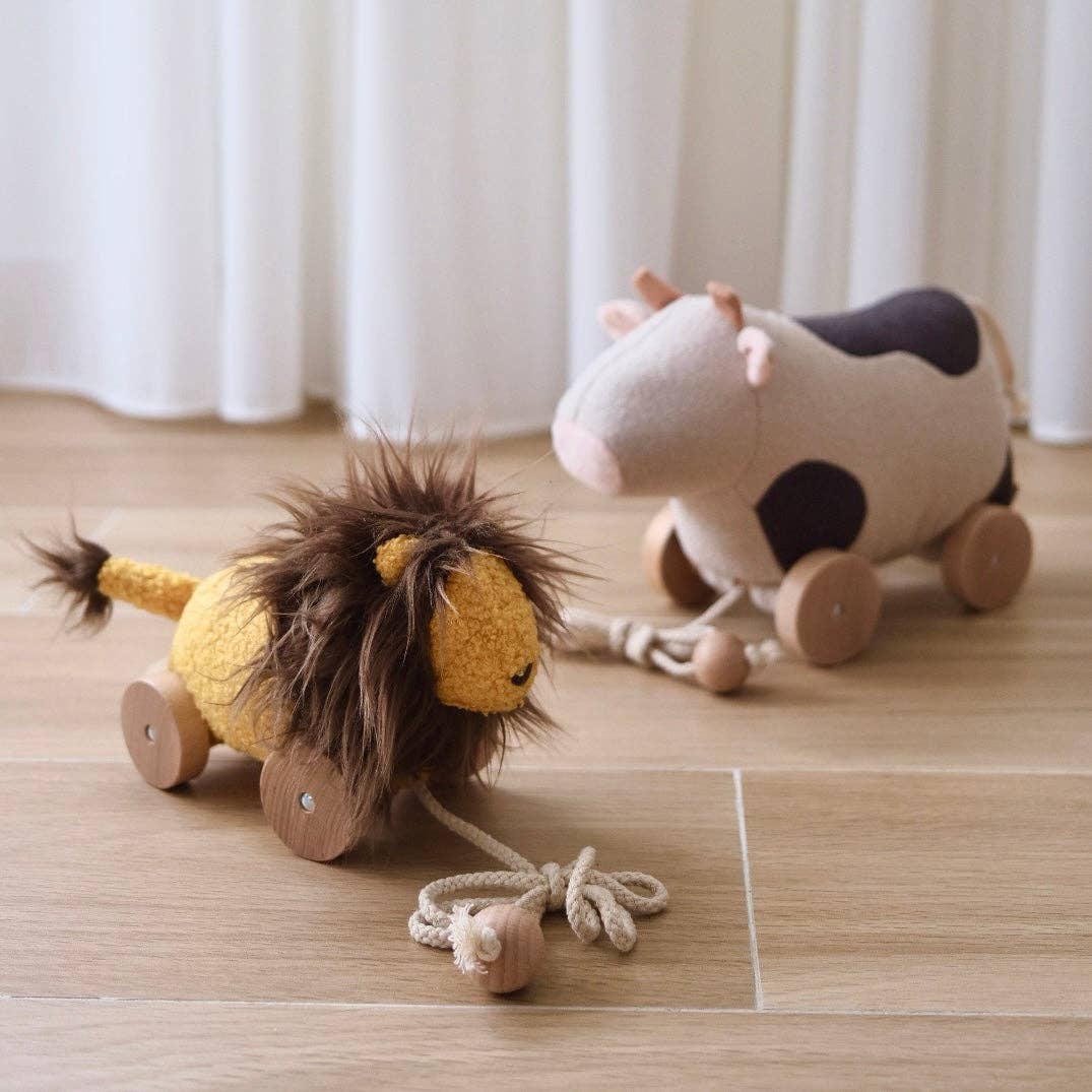 Two plush toys on a wooden floor with white curtains in the background