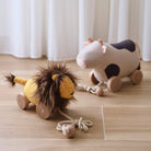 Two plush toys on a wooden floor with white curtains in the background