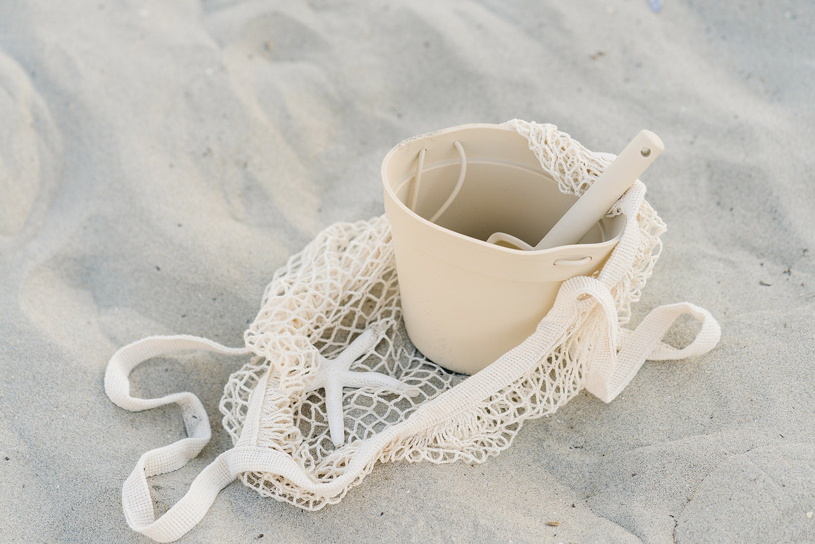 A white bucket and a net on a white sand