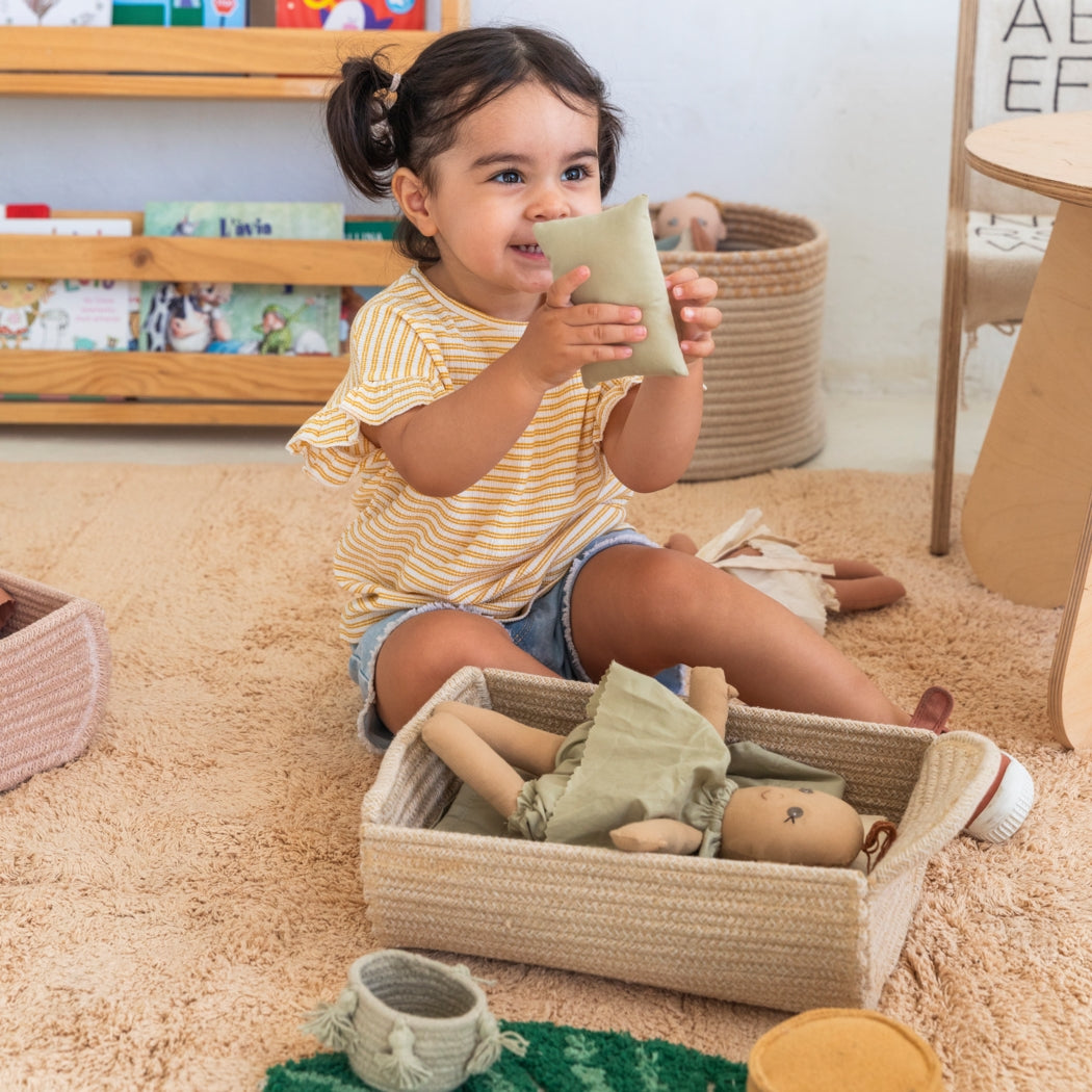 Child playing with toys in a room with books and furniture.