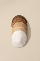 Stack of wooden coasters with a white base on a beige background