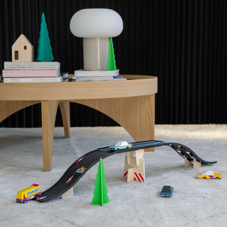 Toy race track set with cars and table on a black wall