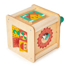 A wooden activity cube by Mentari on a plain white background, featuring a colorful clock face on the front, spinning shape panels on the side, and an illustrated sliding puzzle top.