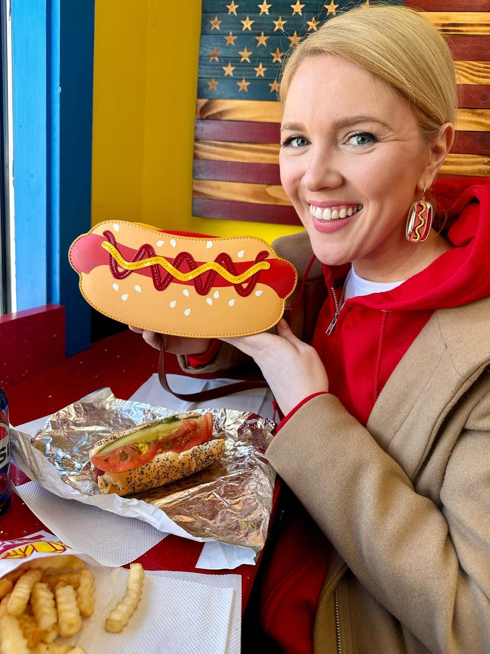 Woman holding a large plastic hot dog with a colorful background