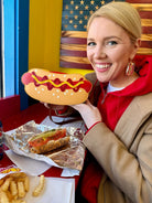 Woman holding a large plastic hot dog with a colorful background