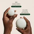 Two hands holding a mini and full-size soap bar with product details on a beige background.