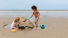 Two children playing with sand toys on a beach.