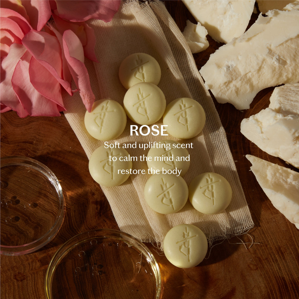 Rose-scented pills on a wooden surface with flowers and a bowl.