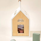 Wooden house-shaped toy with colorful blocks inside, hanging against a light background