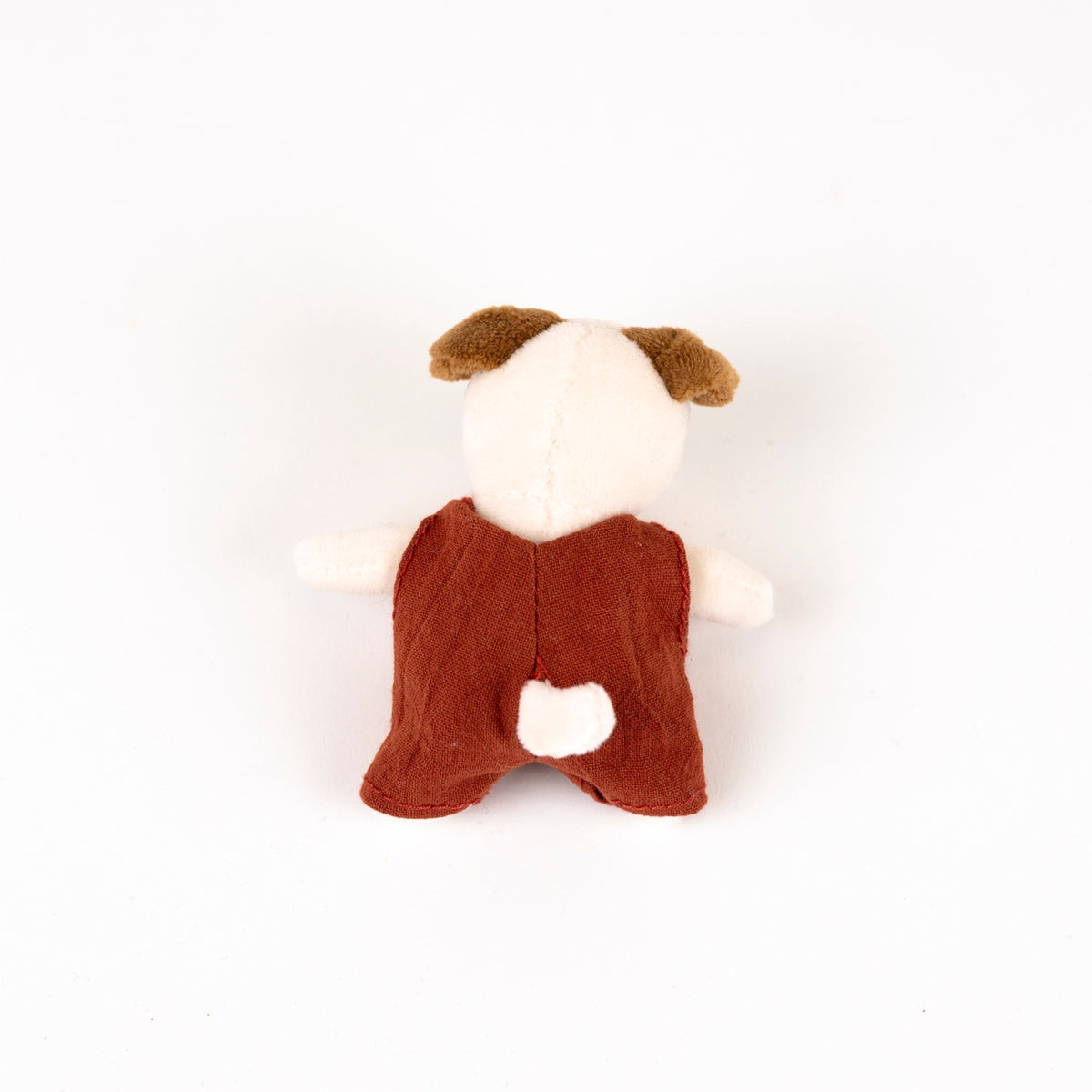 Stuffed toy dog with a red romper on a white background - from the back
