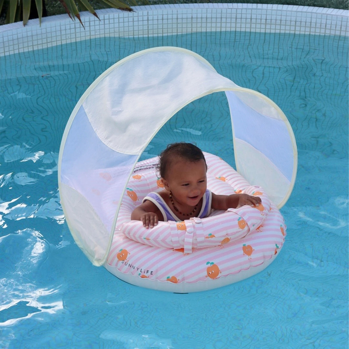 Baby in a inflatable pool seat with canopy in a swimming pool