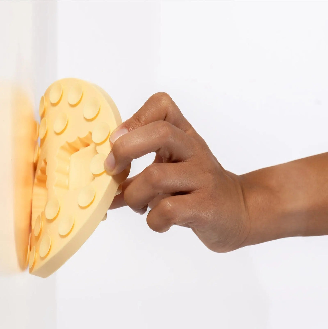 Hand interacting with a heart-shaped light fixture on a white background