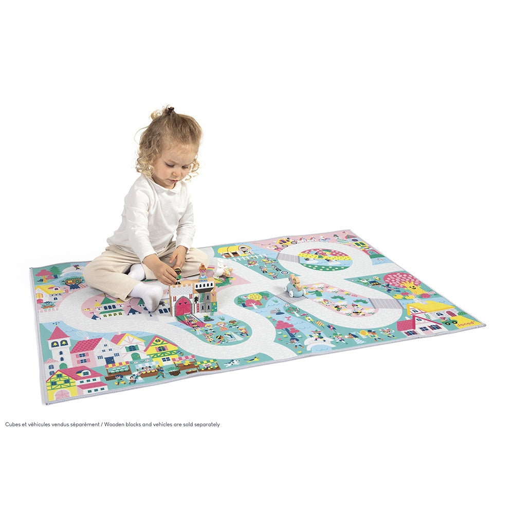 Child playing on a colorful play mat with road designs and small buildings.