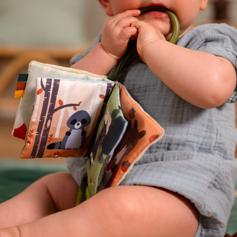 Baby holding a soft book with colorful illustrations, featuring a panda character.