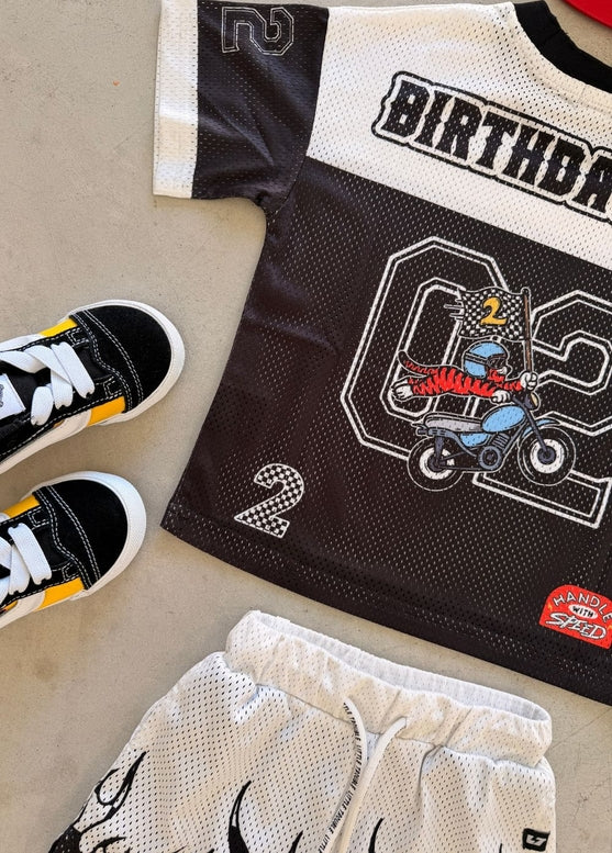 Children's birthday-themed jersey with matching shoes on a neutral background