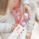 Person holding a box with purple balls inside, wearing a light-colored outfit.