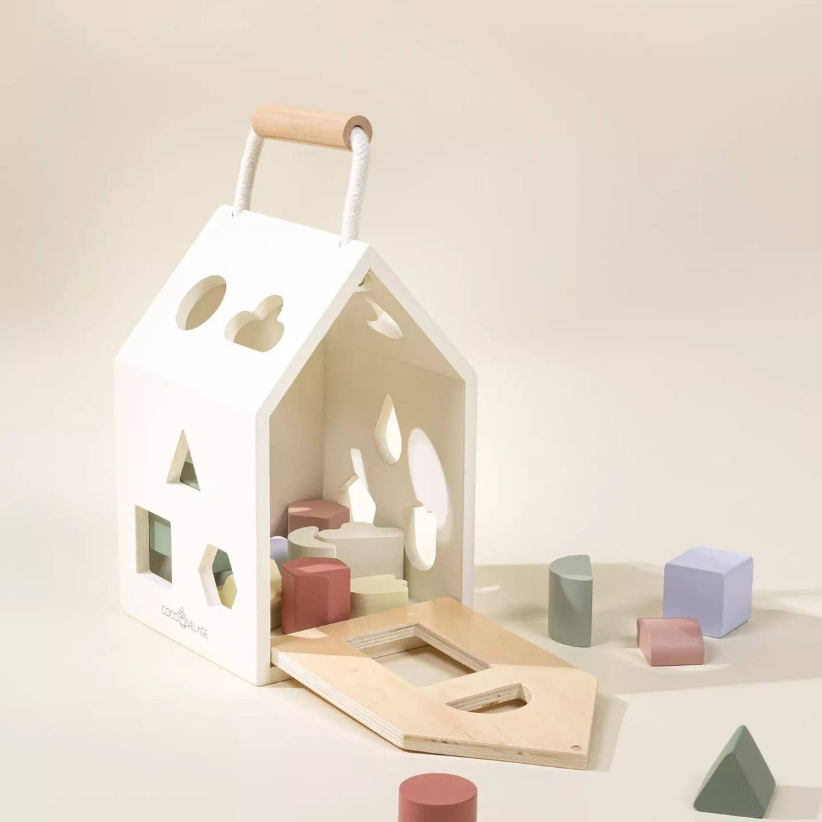 Wooden toy house with geometric blocks on a light background