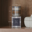 Plaid candle with packaging labeled 'Hello Fall' on a wooden surface with measurements.