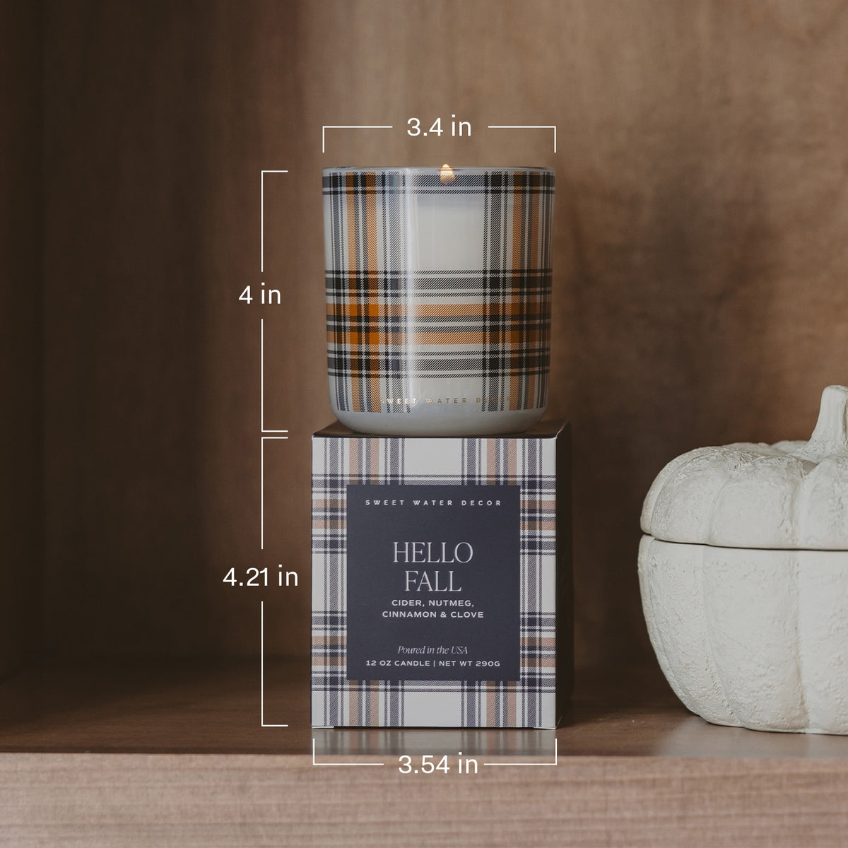 Plaid candle with packaging labeled 'Hello Fall' on a wooden surface with measurements.