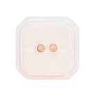 Square pink case with smiley face earrings on a white background