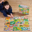 Child playing with a colorful alphabet and dinosaur puzzle on a wooden floor.