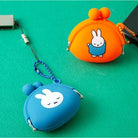 Two small pouches, one orange and one blue, with cartoon character designs on a green background.