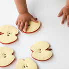 Children's hands interacting with apple-shaped cookies on a white surface
