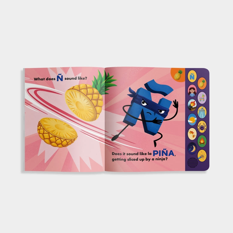 A child holding open "What Does Ñ Sound Like?: A Spanish-English Sound Book," showing an interior illustrated spread featuring an animated letter Ñ character, flying pineapples, and the text "Does it sound like la PIÑA, getting sliced up by a ninja?" on the right, with a vertical panel of sound buttons on the right edge.