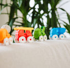 Colorful toy cars on a white surface with green plants in the background