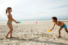Two children playing on a sandy beach with toys.