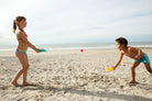 Two children playing on a sandy beach with colorful toys.