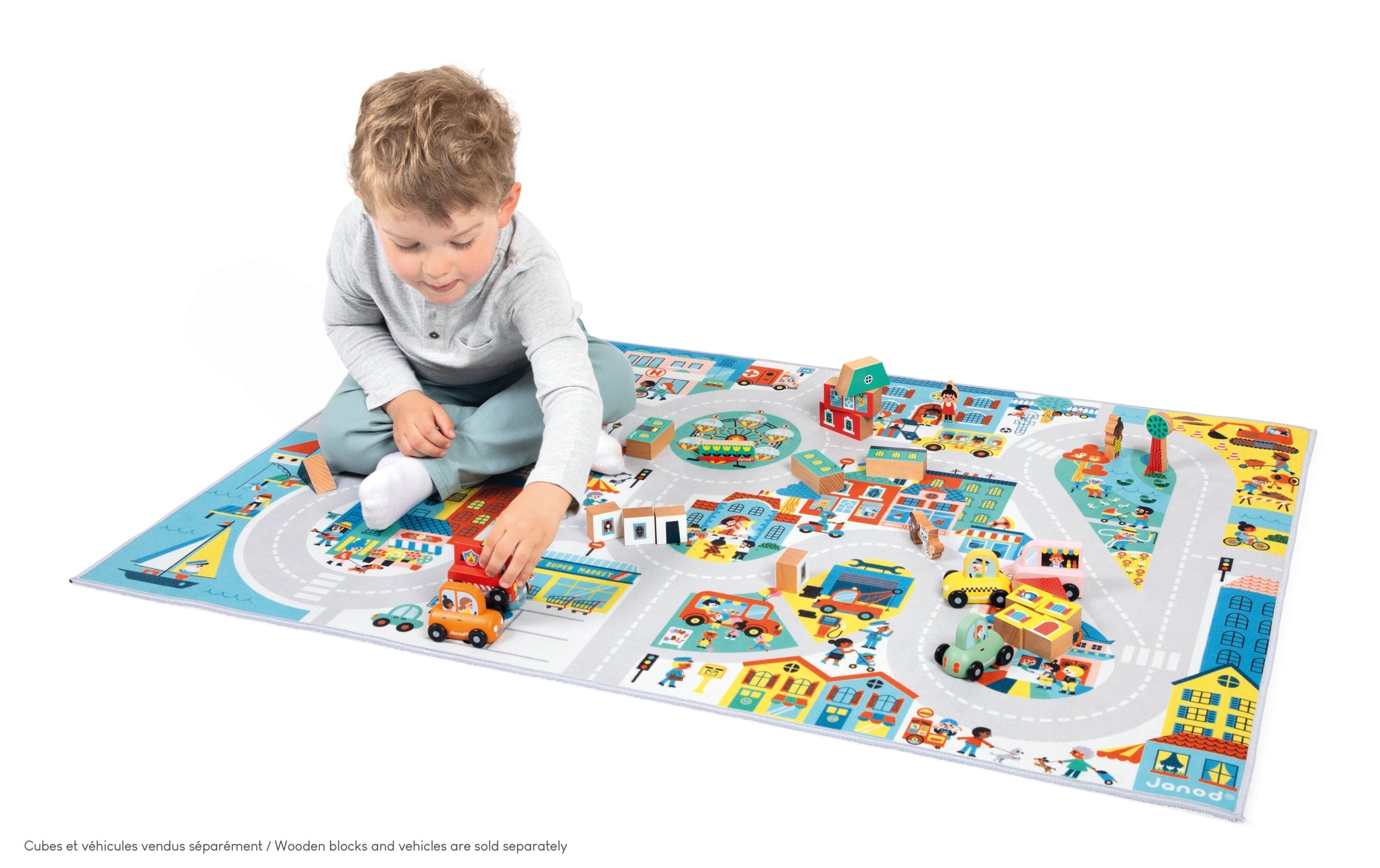 Child playing with a colorful toy mat featuring roads and buildings.