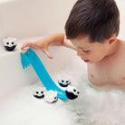 Child playing with penguin bath toys and a blue slide in a bathtub.