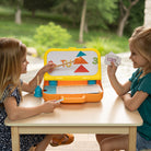 Two children playing with a educational toy at a table outdoors.