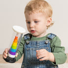 Child holding a colorful hourglass toy against a plain background